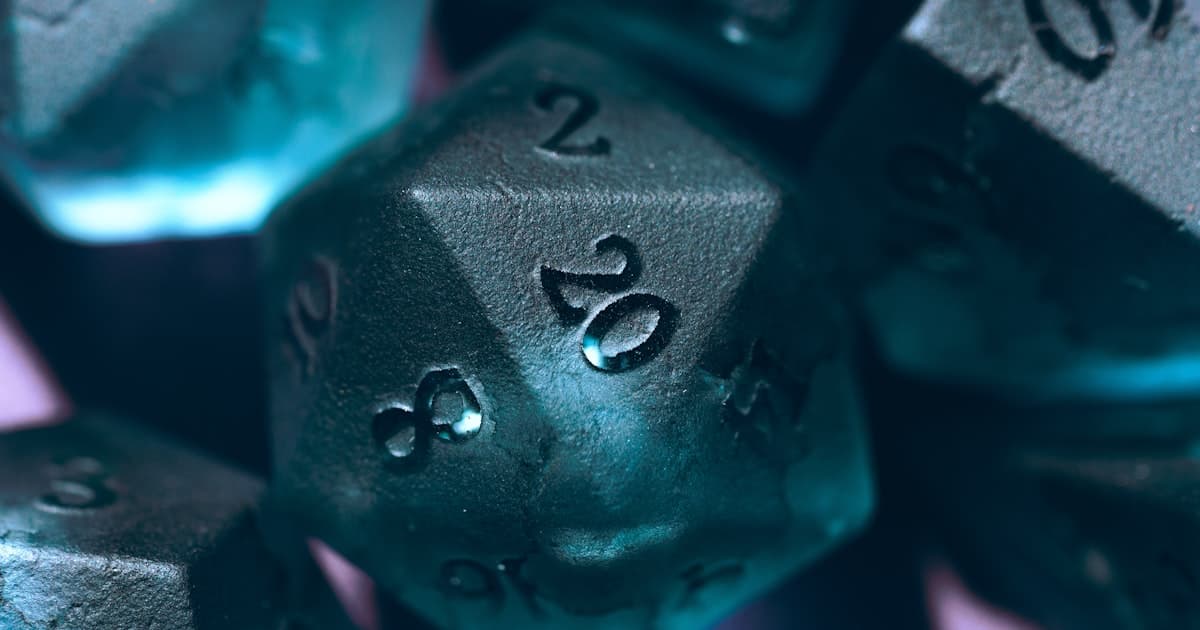 Close-up of dark teal polyhedral gaming dice with a d20 showing 20