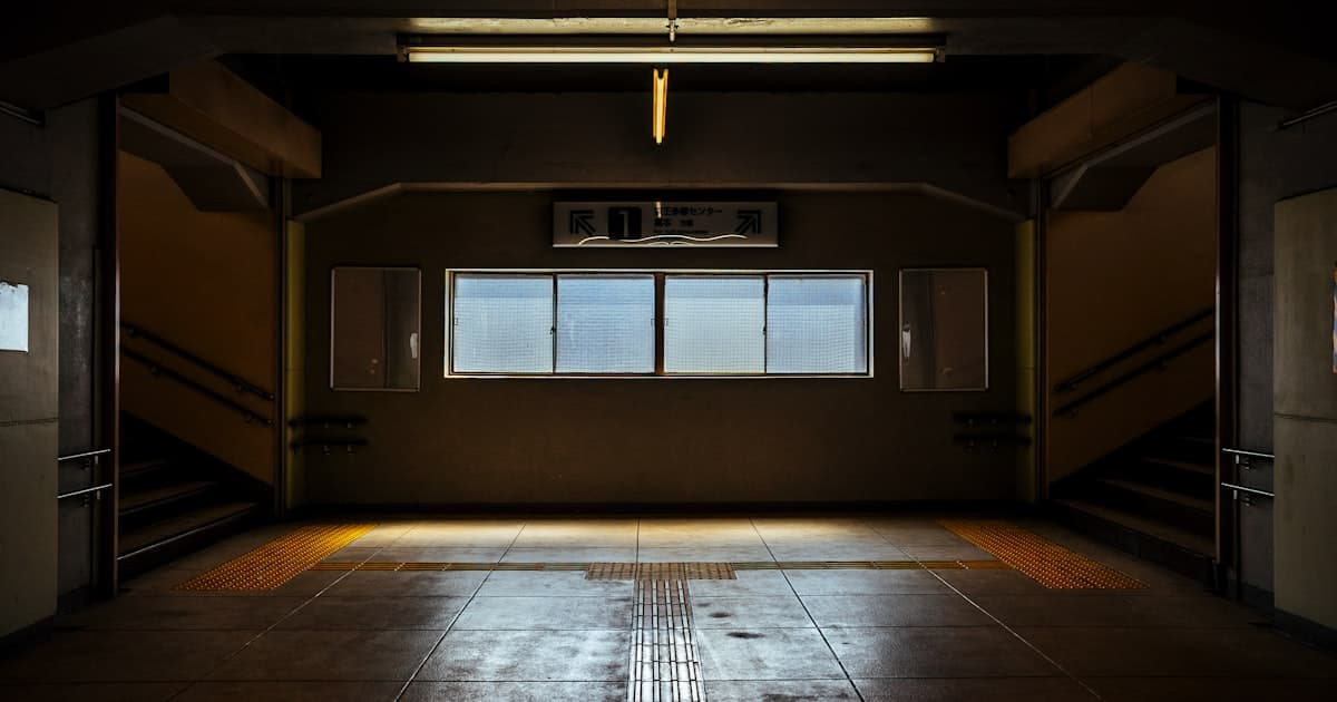 A dark, empty corridor with stairs and a window