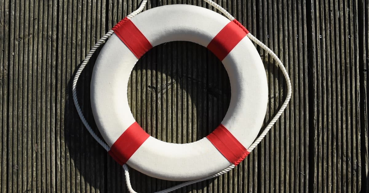 A white and red life ring mounted on a wooden wall