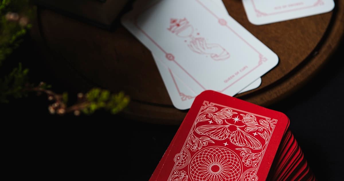 A red deck of playing cards face-down on a dark wooden table
