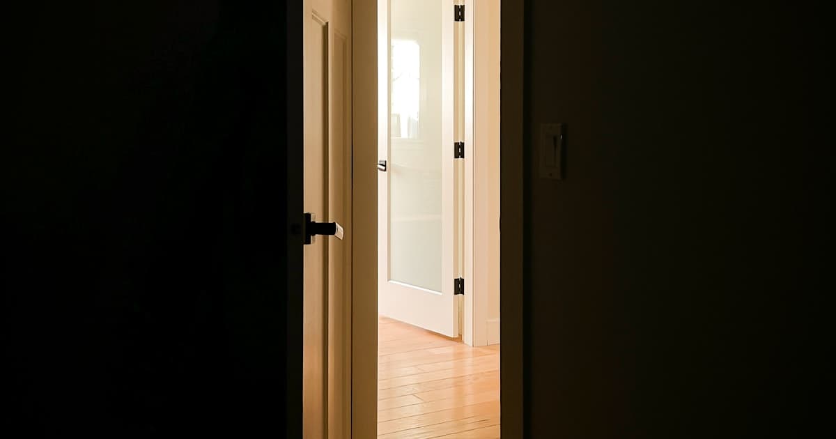 A door slightly ajar with warm light coming through