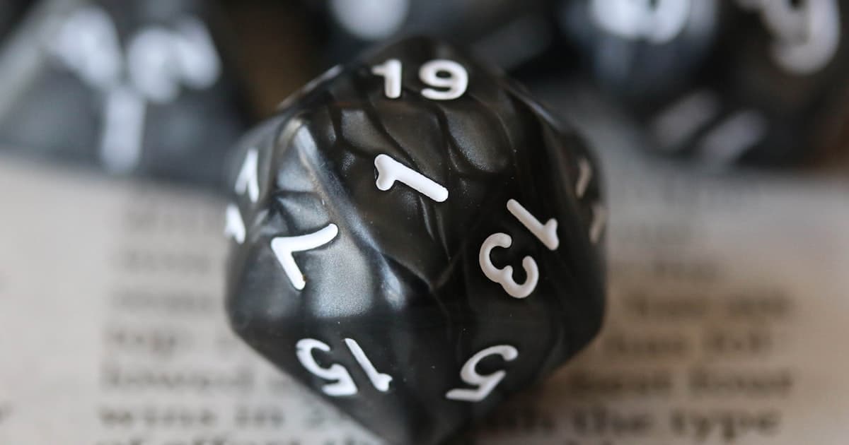 A twenty-sided die resting on a printed rulebook page