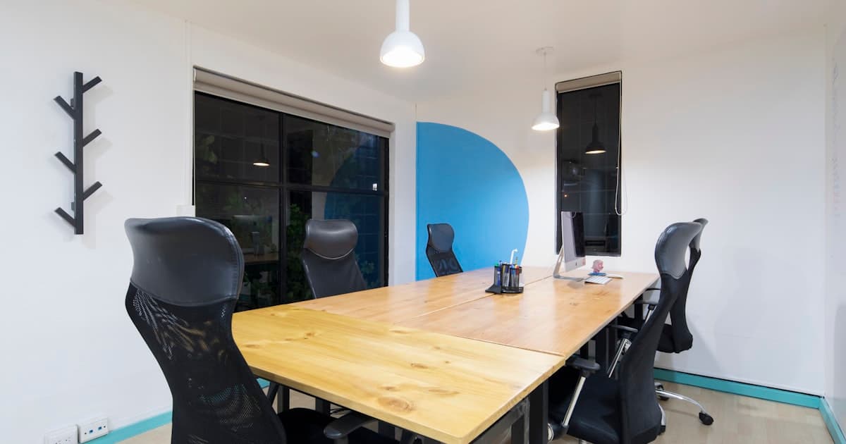 An empty meeting room with black office chairs around a wooden conference table